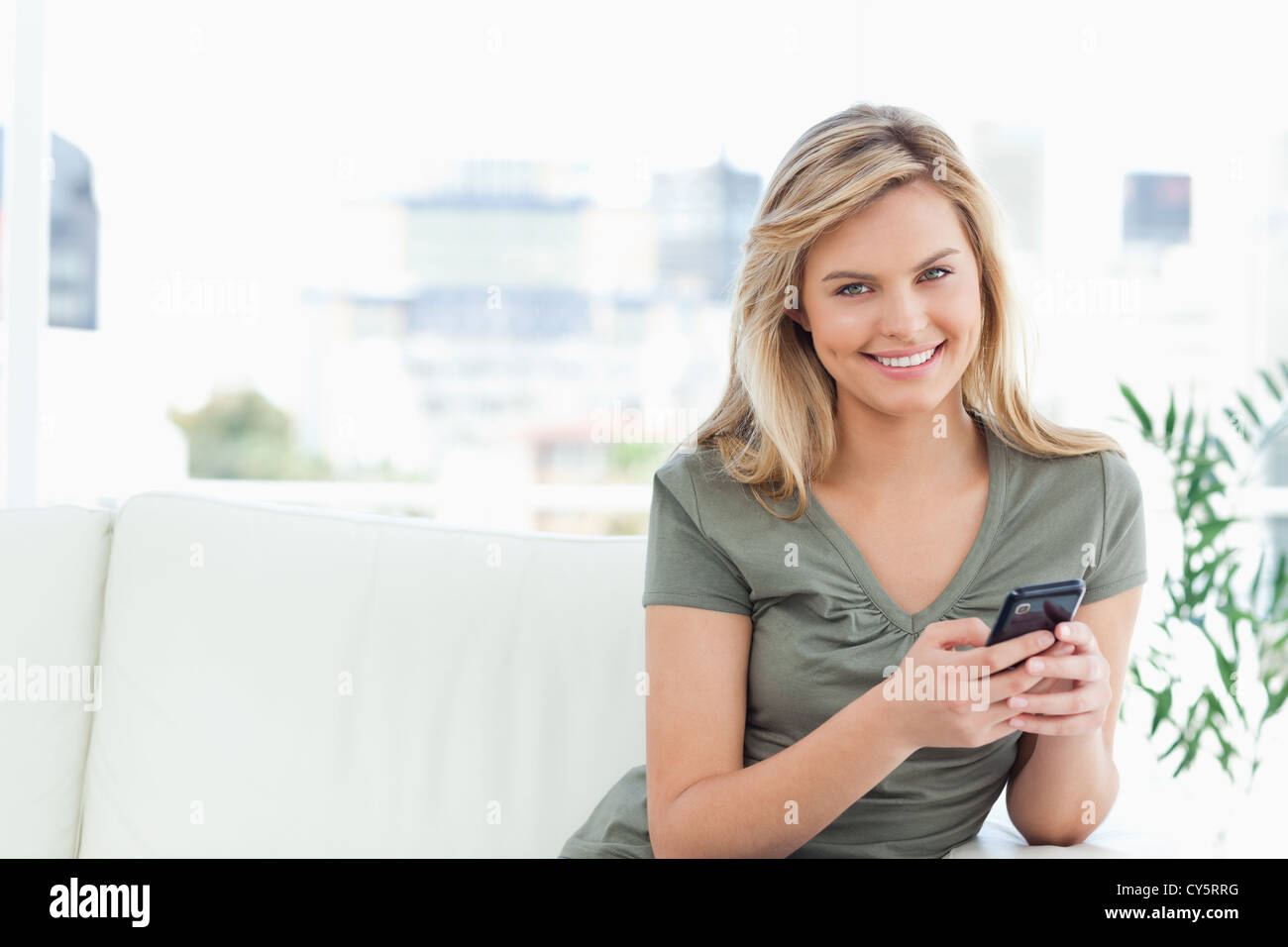 Frau geradeaus schauen und Lächeln, als sie ihr Handy benutzt Stockfoto