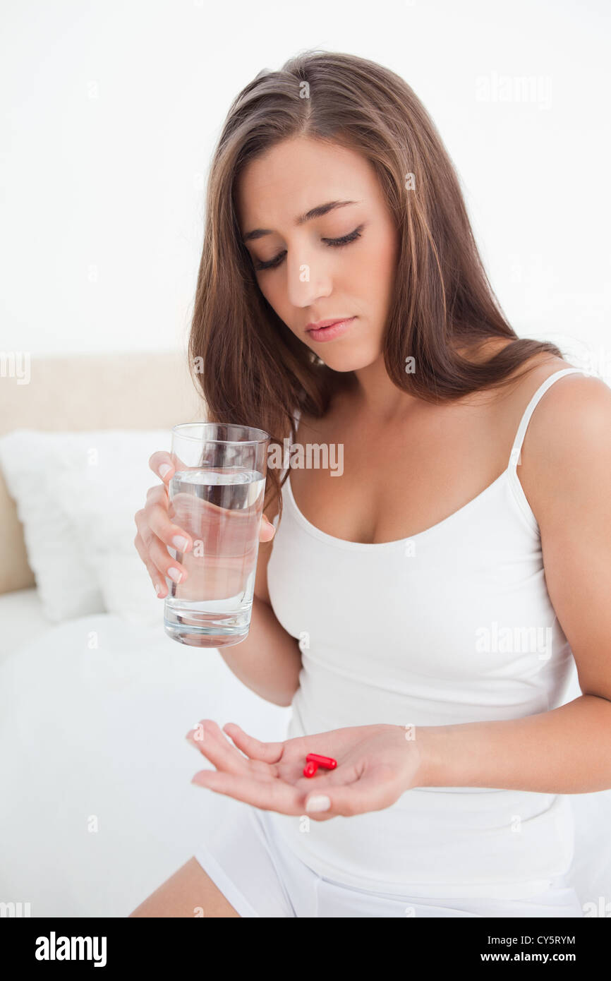 Frau blickte auf die zwei Pillen wird sie mit Wasser zu nehmen Stockfoto