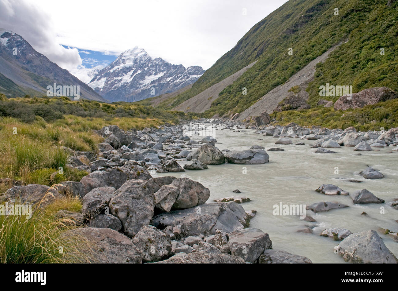 Eiskalte Wasser fließt entlang der Hooker Valley stromabwärts des Hooker-Gletschers, mit der majestätischen Gipfel des Mt. Cook in der Ferne Stockfoto