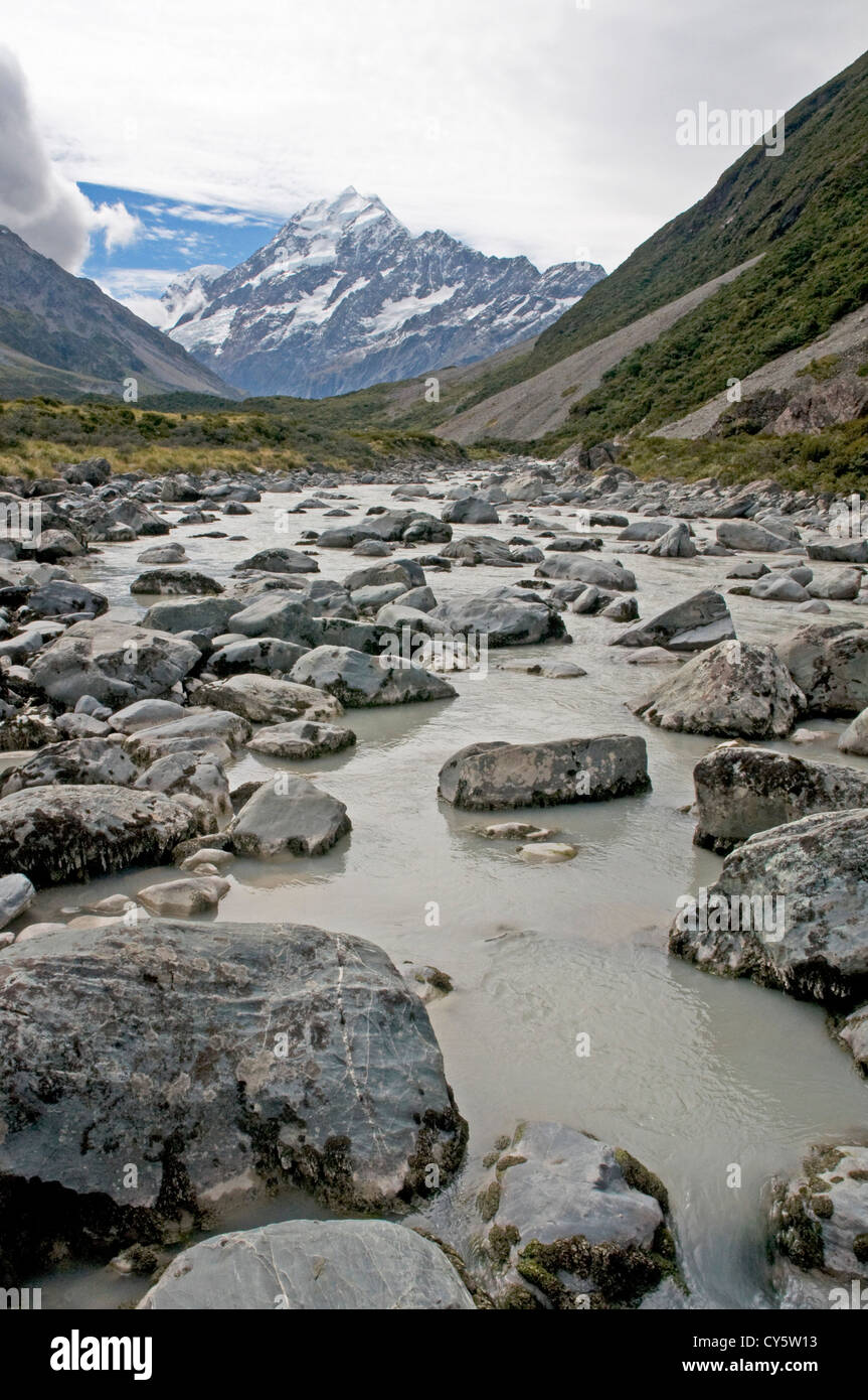 Eiskalte Wasser fließt entlang der Hooker Valley stromabwärts des Hooker-Gletschers, mit der majestätischen Gipfel des Mt. Cook in der Ferne Stockfoto