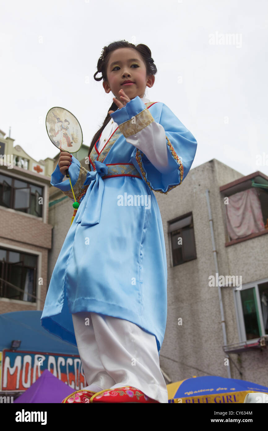 Junge Mädchen, die Teilnahme an Kinderumzug während Cheung Chau Bun Festival Stockfoto