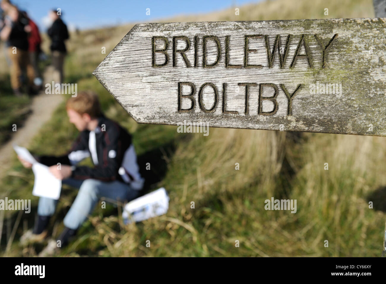 Sign post zeigt den Maultierweg zu Boltby in North Yorkshire Moors in der Nähe von Sutton Bank und Wanderer, die Überprüfung ihrer Karten. Stockfoto