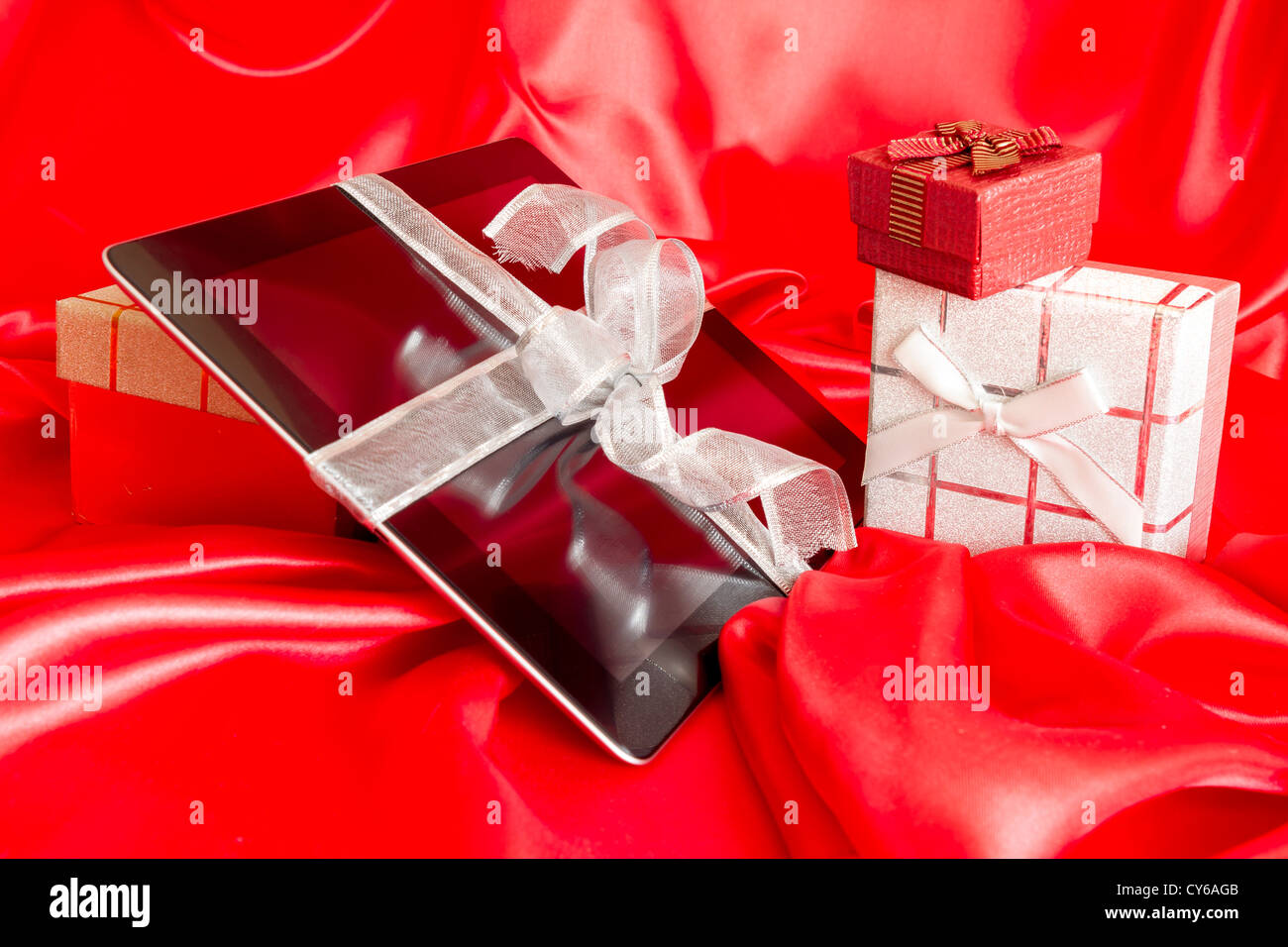Digital-Tablette mit Weihnachtsgeschenk auf rotem Grund Stockfoto