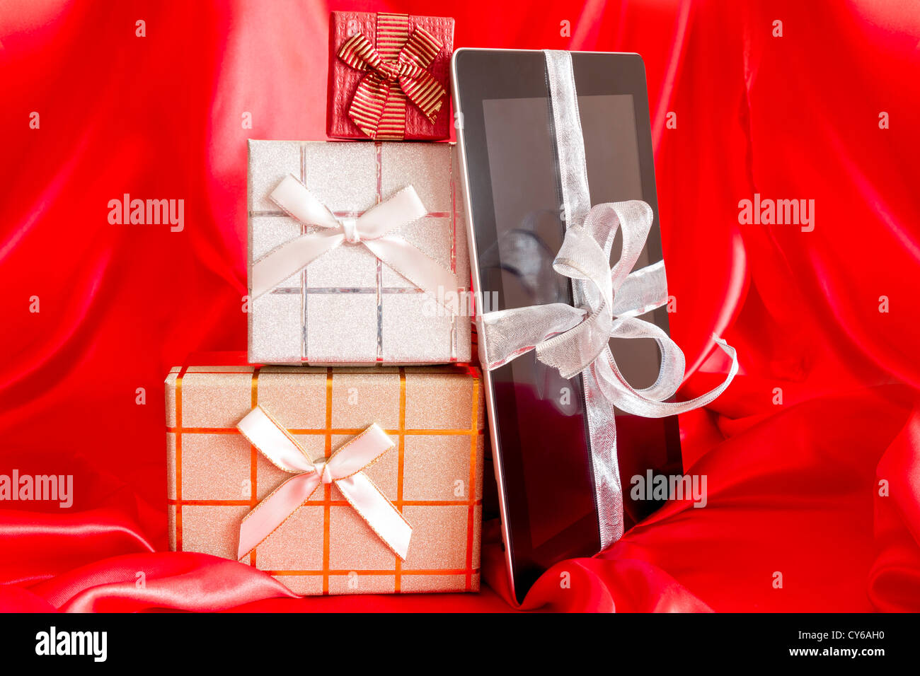 Digital-Tablette mit Weihnachtsgeschenk auf rotem Grund Stockfoto