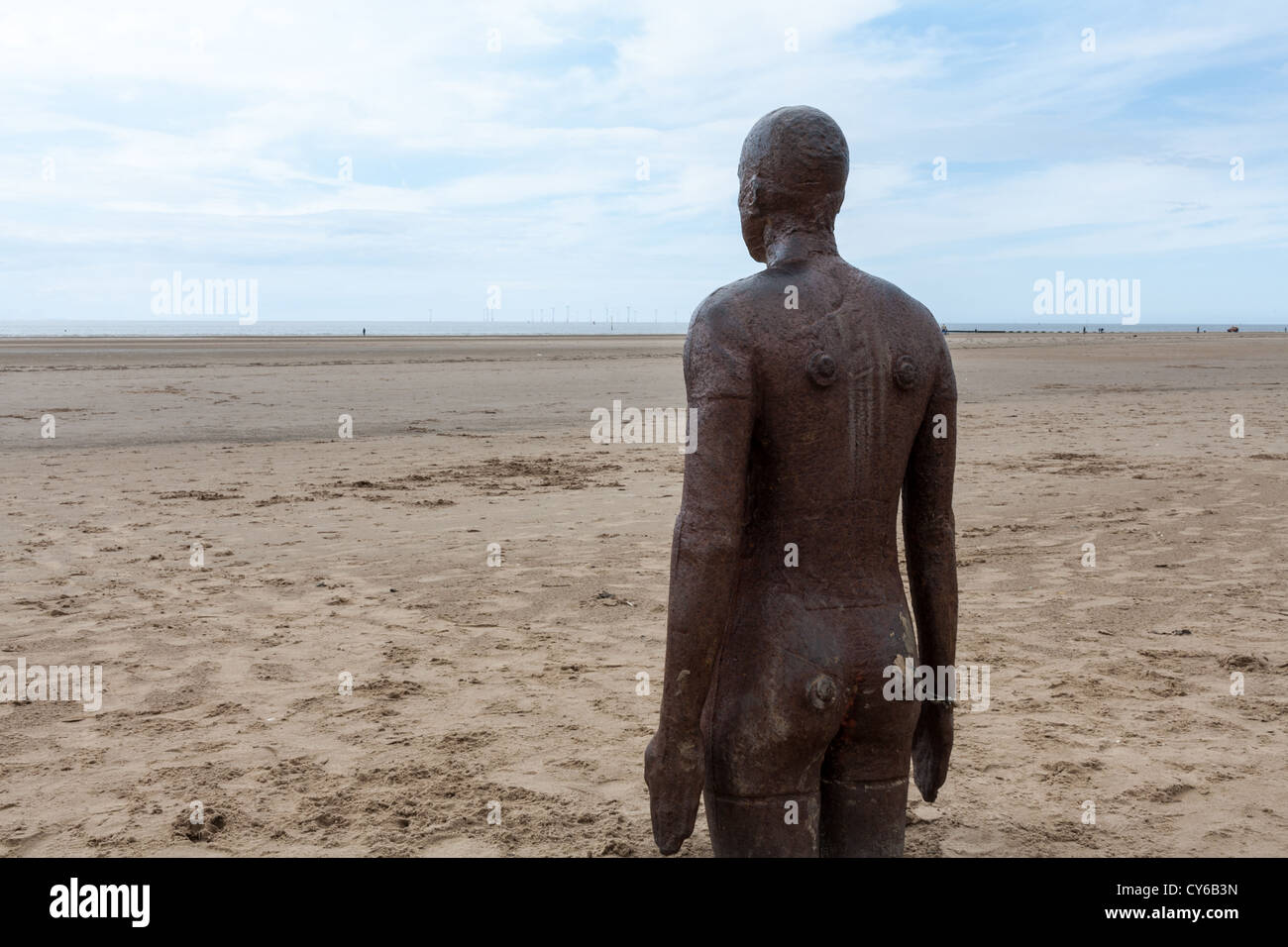 Eine der gusseisernen Figuren von einem anderen Ort, ein Stück moderner Skulptur von Antony Gormley am Strand von Crosby. Stockfoto