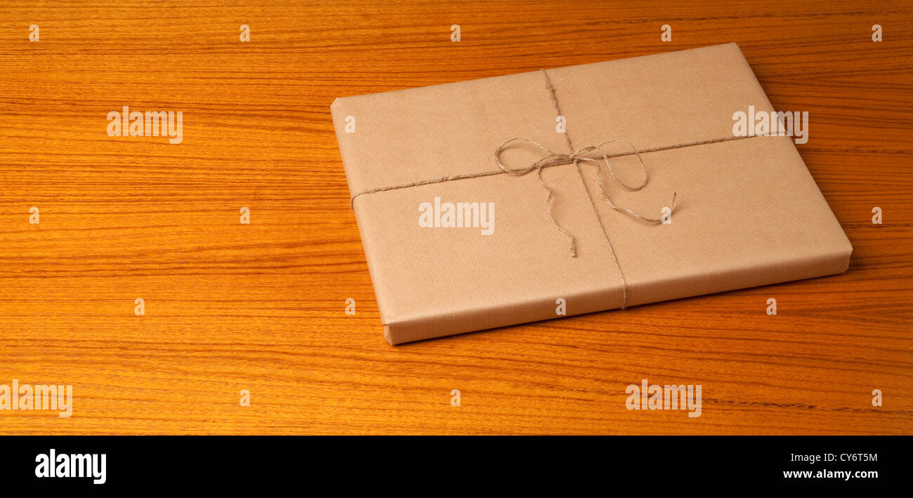 braune Geschenk-Paket auf einem Holztisch mit Körnung Muster Stockfoto