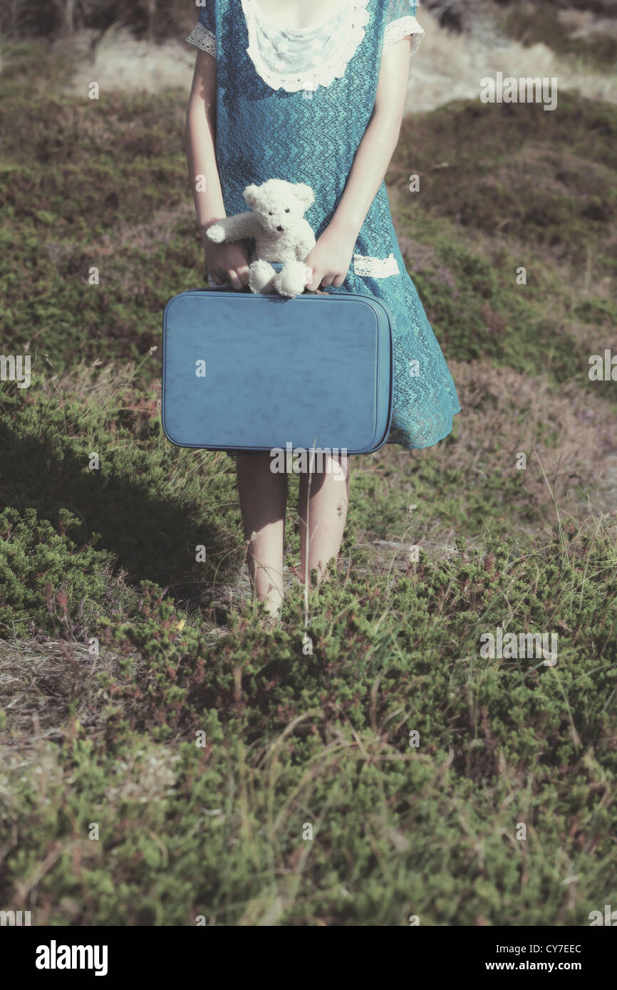 ein junges Mädchen mit einem Koffer und ein Teddybär Stockfoto
