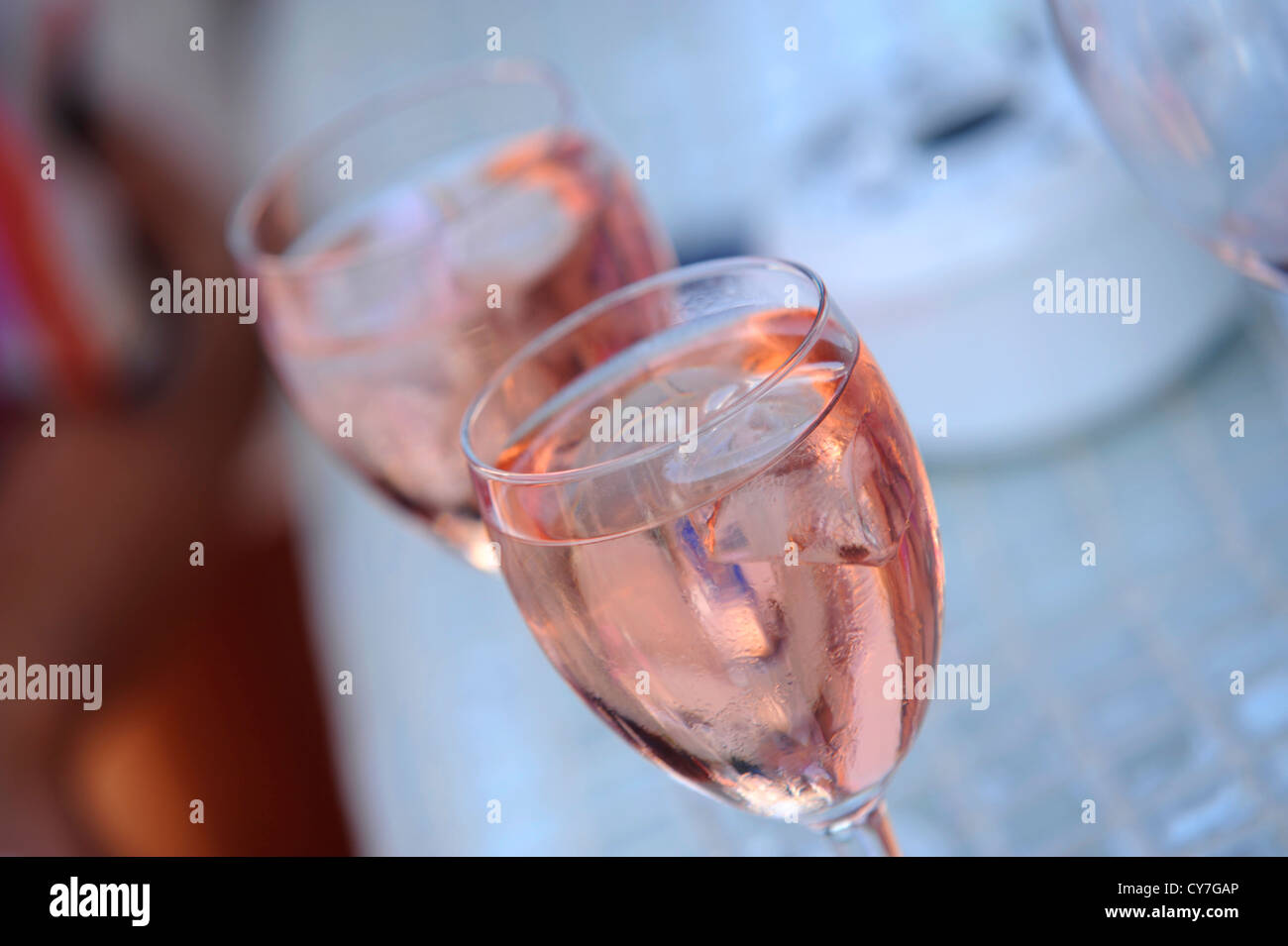 voller Licht 2 Gläser Wein Pink-Rose gefärbt mit Eiswürfeln, mit einem unscharf Stockfoto