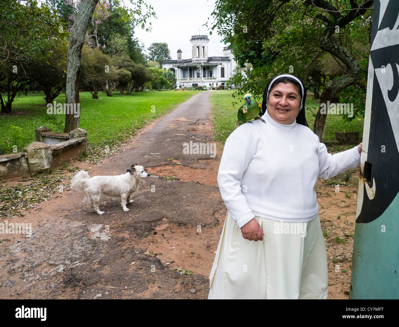 Eine Dominikanische Nonne steht auf dem Gelände der Castillo de Carlota Robins mit ihrem Papagei und Hund in Areguá, Paraguay. Stockfoto