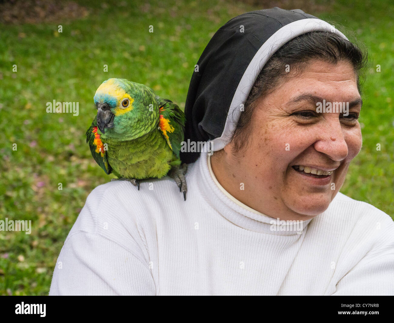 Eine Dominikanische Nonne steht auf dem Gelände der Castillo de Carlota Robins mit einem Papagei auf der Schulter in Areguá, Paraguay. Stockfoto