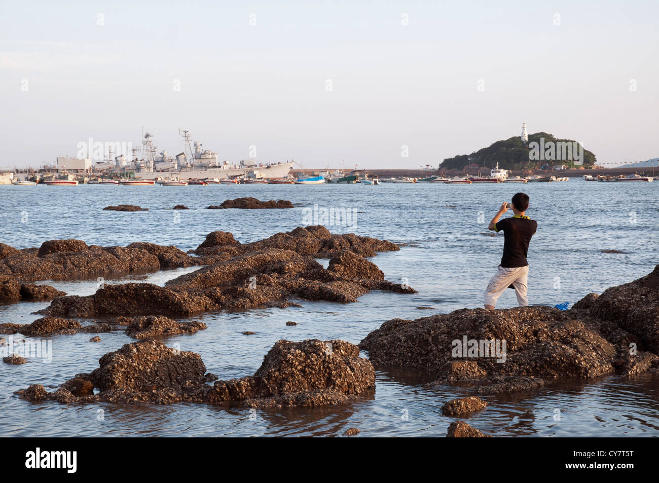 Ein Tourist nimmt ein Bild eines chinesischen Zerstörers in Qingdao Bucht vor Anker, Qingdao, China Stockfoto