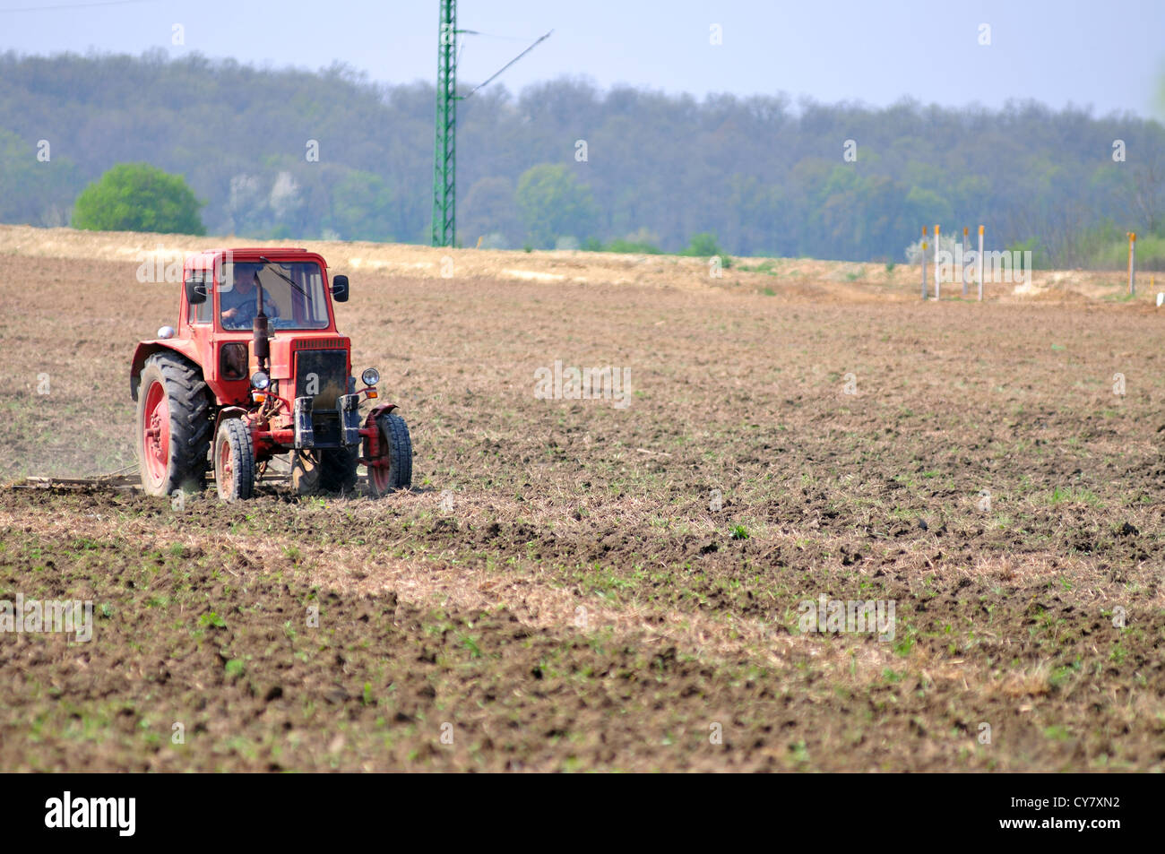 Roter Traktor auf einem Feld im zeitigen Frühjahr, die Vorbereitung der Flächen für die neue Ernte Stockfoto