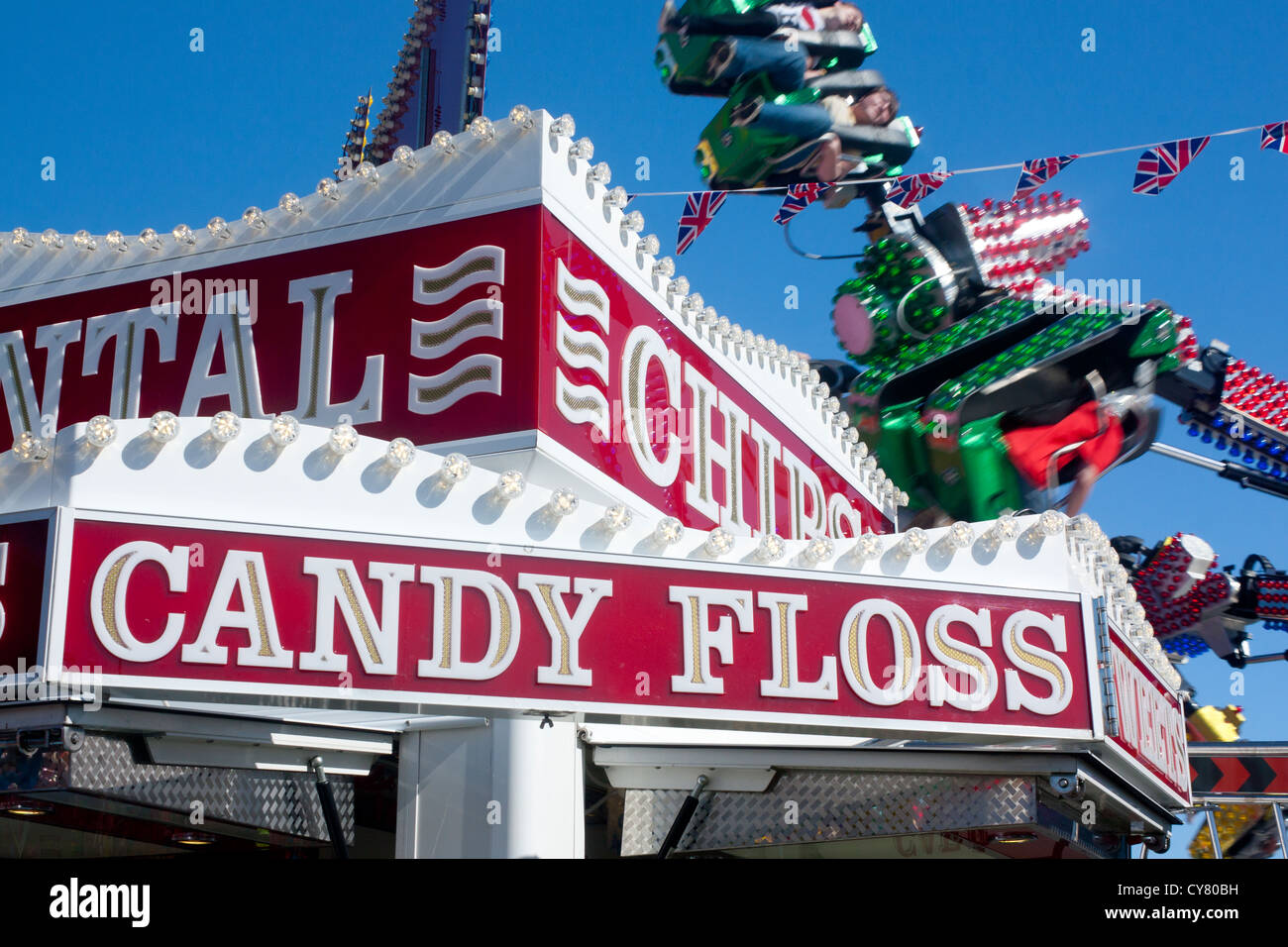 Zuckerwatte und Chips Schild am Imbissstand in Kirmes mit Fahrt hinter Stockfoto