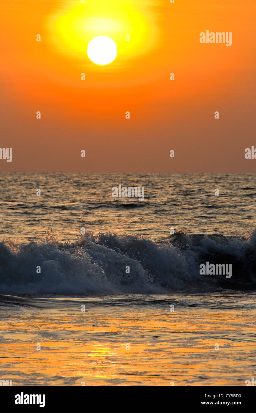 Vertikale Blick auf den Sonnenuntergang über den tosenden Wellen in Kerala, Indien. Stockfoto