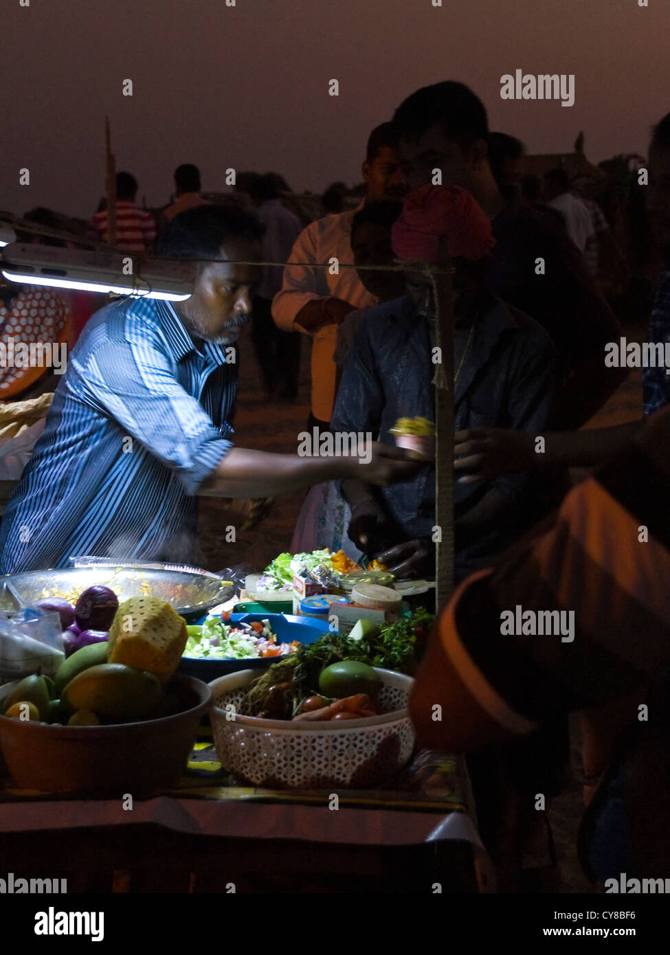 Vertikale Porträt eines fleißigen indischen Mannes Verkauf von Fast-Food an einem Stand am Strand von Kovalam. Stockfoto