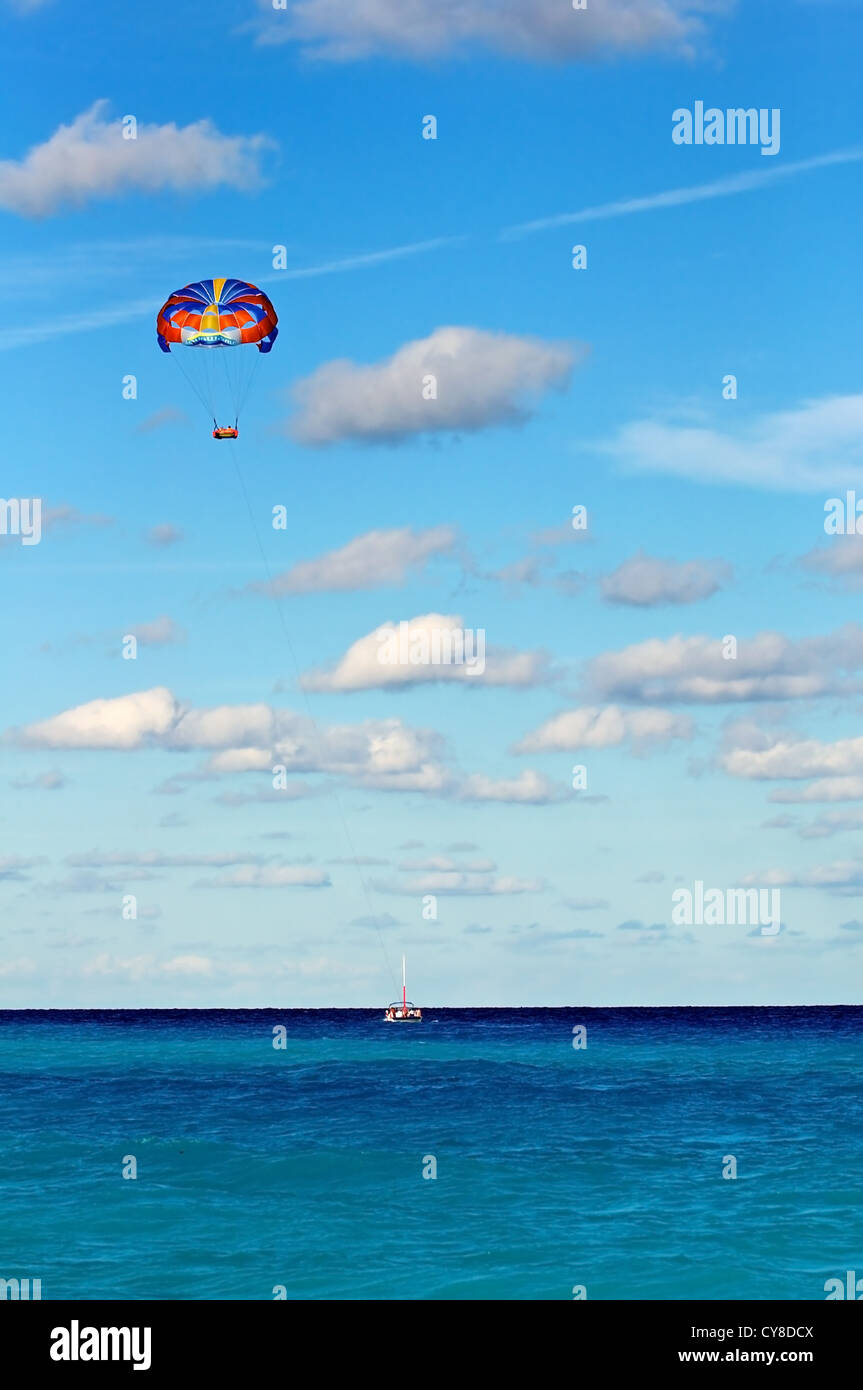 Parasailing hoch über ein Boot über einen türkisfarbenen Meer geschleppt Stockfoto