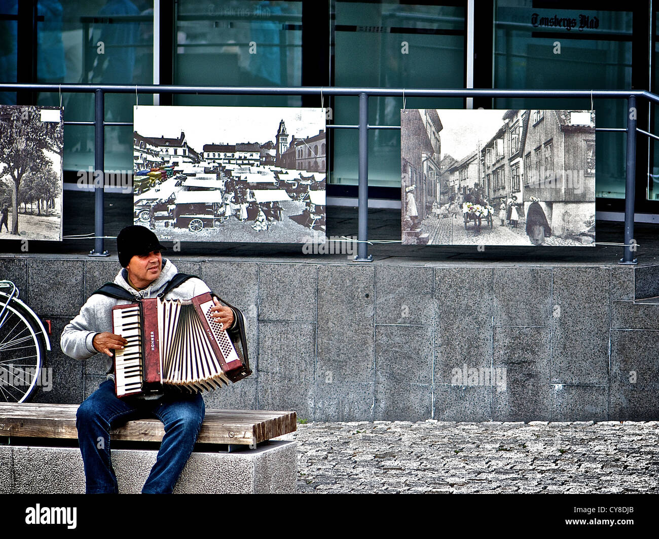 Ein Akkordeon Straßenmusiker spielt in einem Stein Straße mit schönen Gemälden im Hintergrund Stockfoto