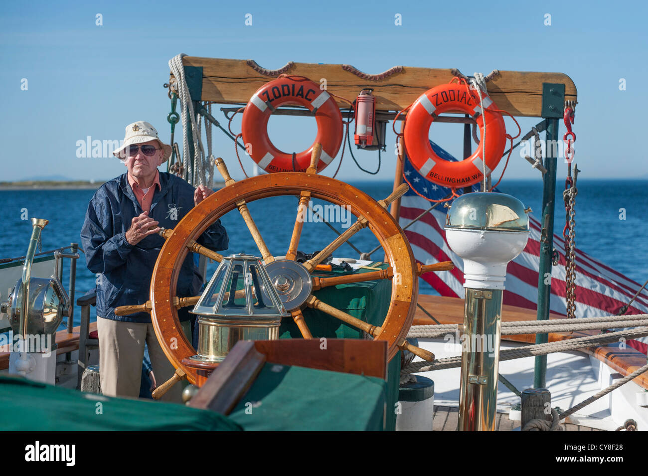 Ein älterer Herr übernimmt das Steuer des historischen Schoners 'Zodiac' Segeln die San Juan Islands of Puget Sound, Washington, USA Stockfoto