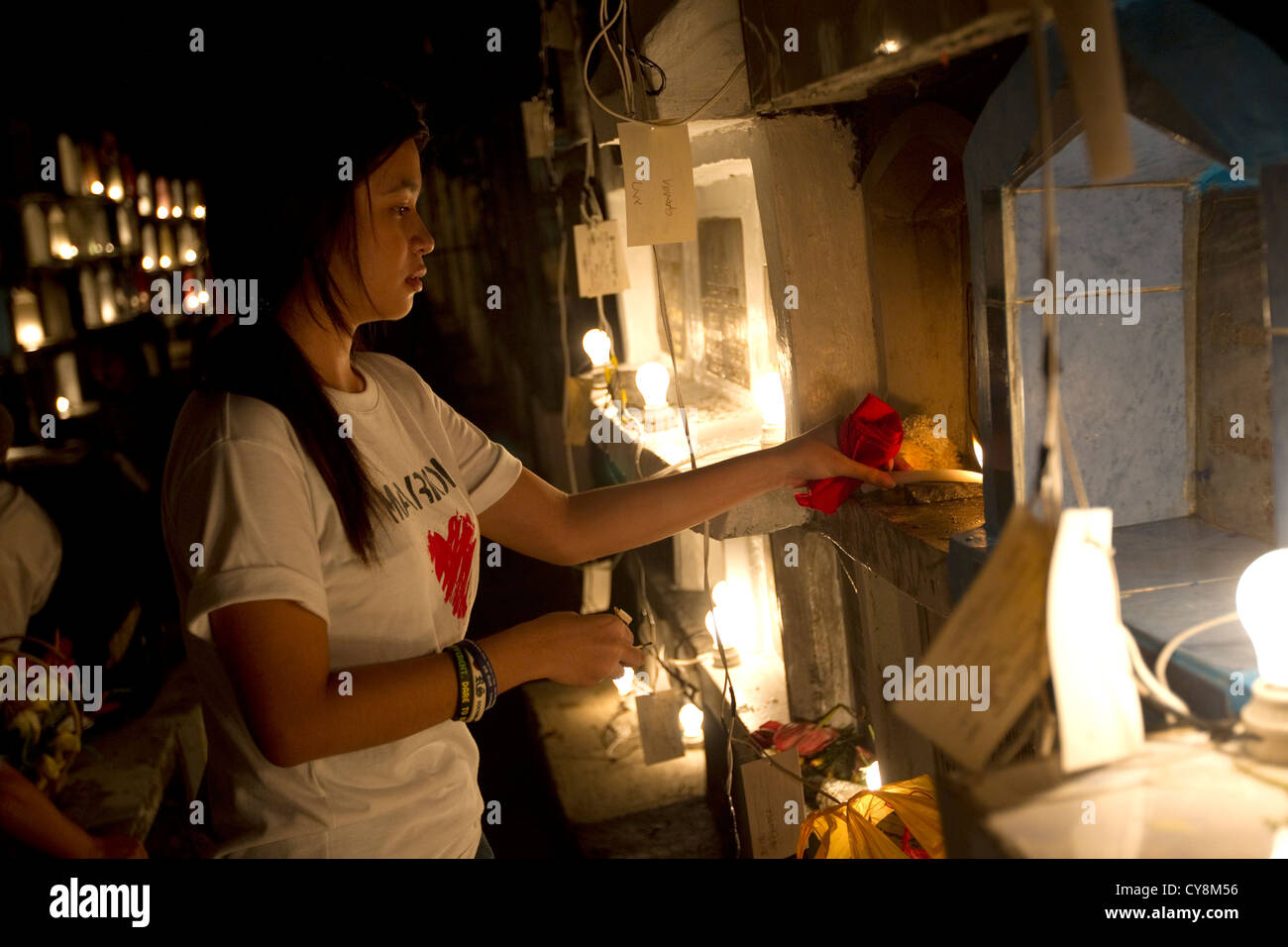 Die philippinischen Mädchen leuchtet eine Kerze am Grab eines Verwandten, Carreta cmetery, Cebu City, Philippinen Stockfoto