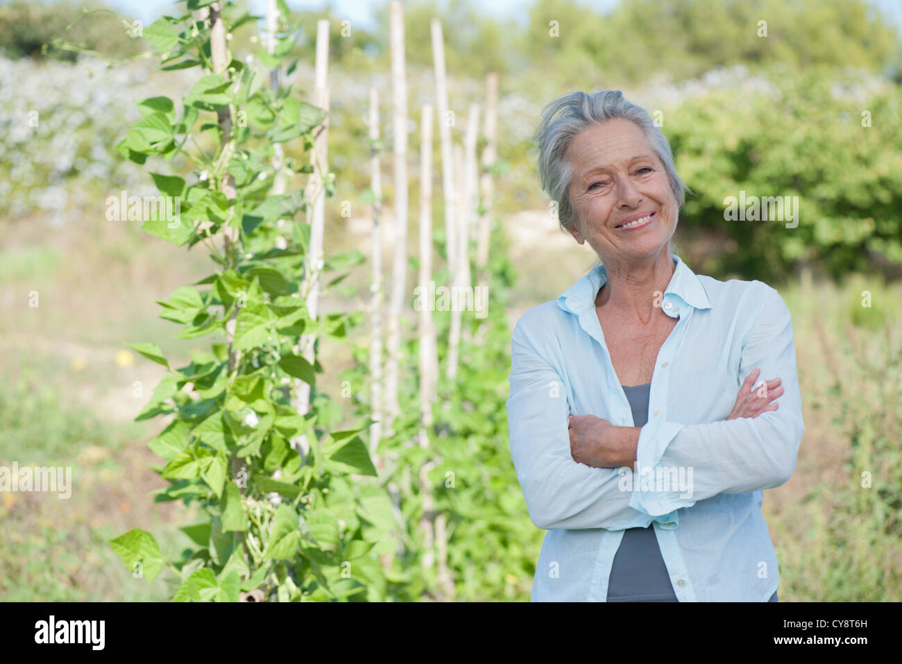 Ältere Frau lächelt stolz im Gemüsegarten Stockfoto