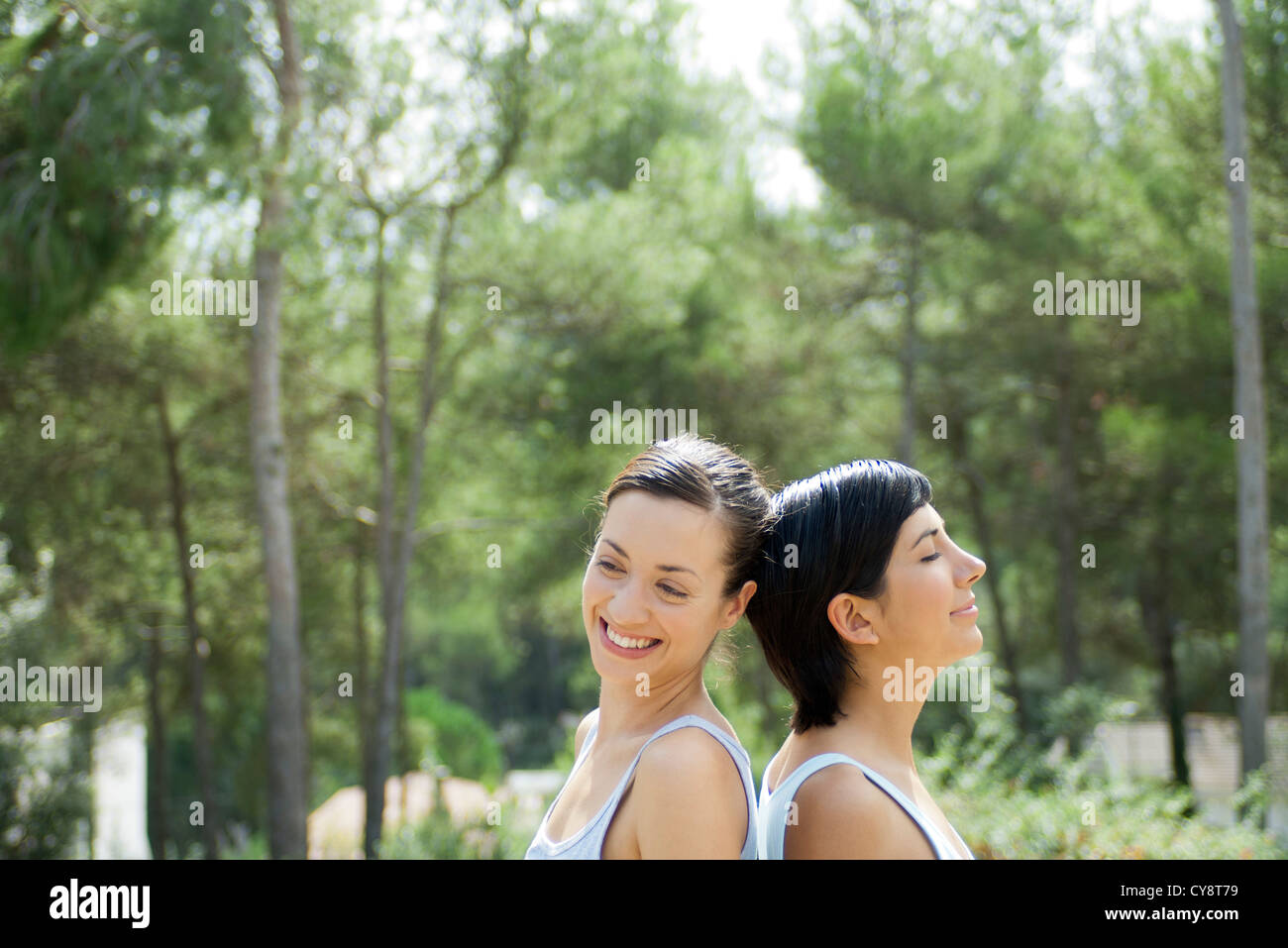 Zwei junge Frauen sitzen Rücken an Rücken im freien Stockfoto