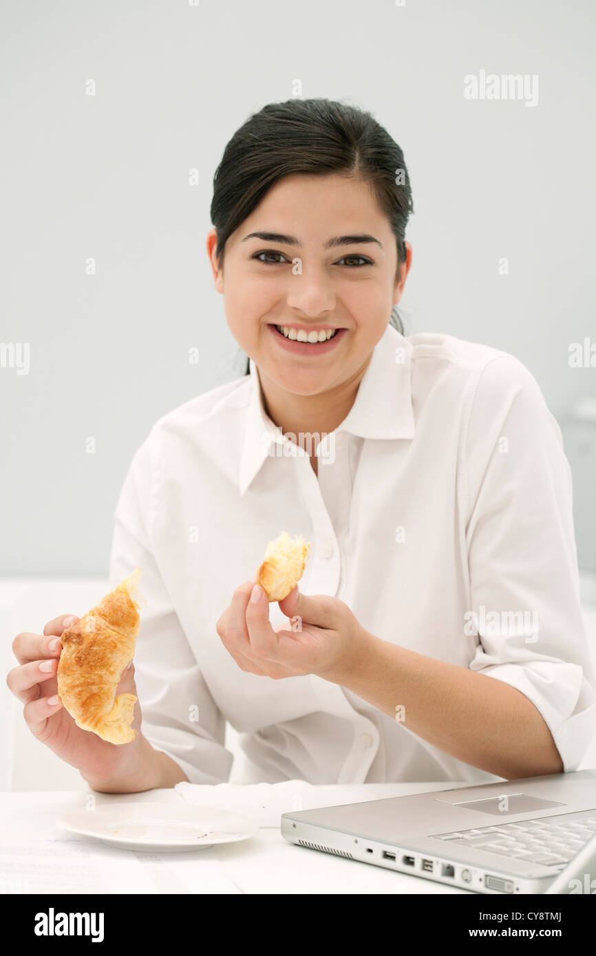 Junge Frau Essen Croissant, Lächeln Stockfoto