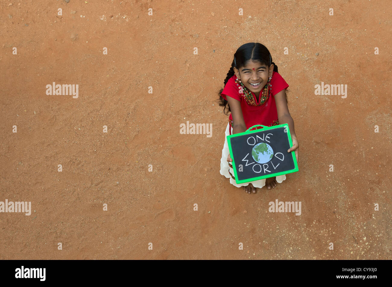 Indianerdorf Mädchen mit ONE WORLD geschrieben auf einer Tafel in einem indischen Dorf. Andhra Pradesh, Indien. Kopieren Sie Raum. Stockfoto