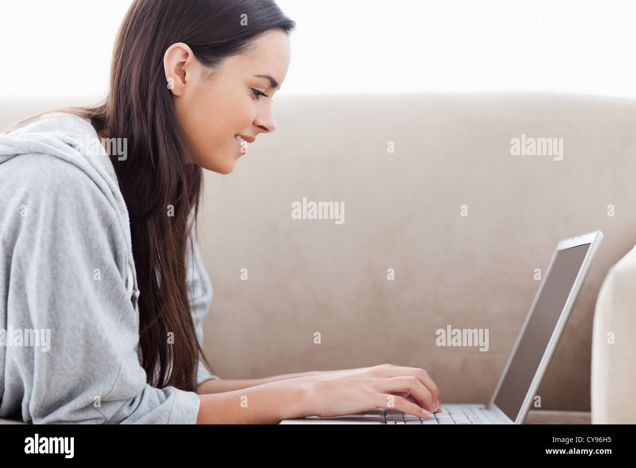 Frau, die Eingabe auf ihrem Laptop auf der Couch liegend Stockfoto