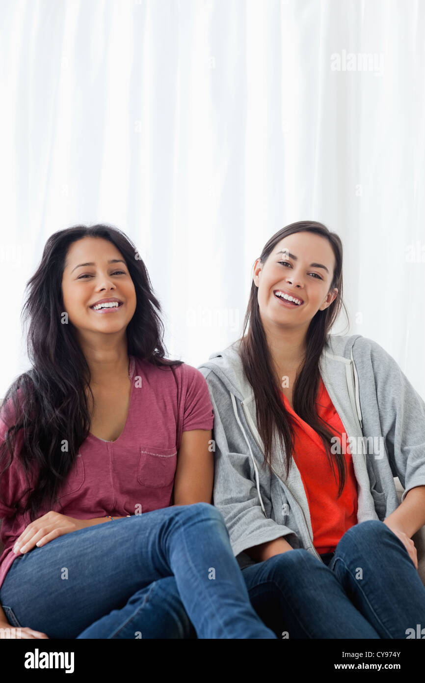 Zwei Frauen auf der Couch zu lachen, als sie geradeaus schauen Stockfoto
