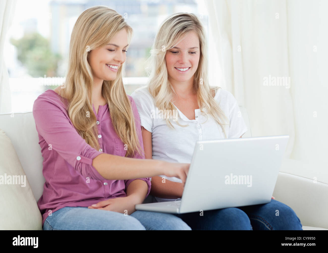 Zwei lächelnde Frauen mit einem Laptop als einem Punkte auf dem Bildschirm Stockfoto