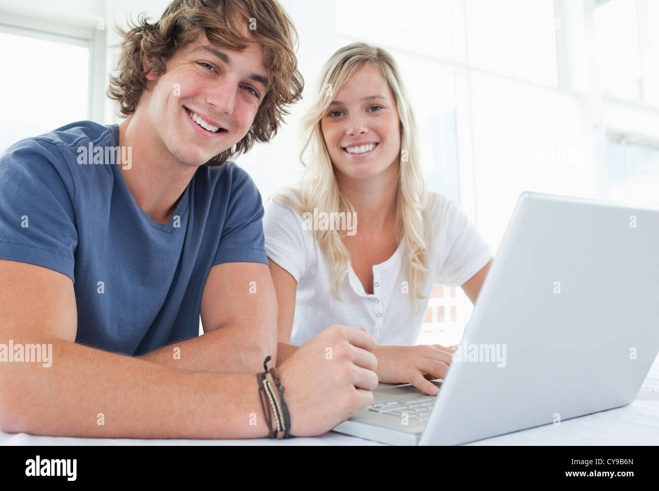 Ein lächelndes paar mit einem Laptop in die Kamera schaut Stockfoto