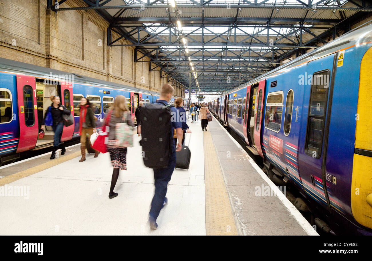 Menschen hetzen, um einen Zug auf dem Bahnsteig, Bahnhof Kings Cross, London UK Stockfoto