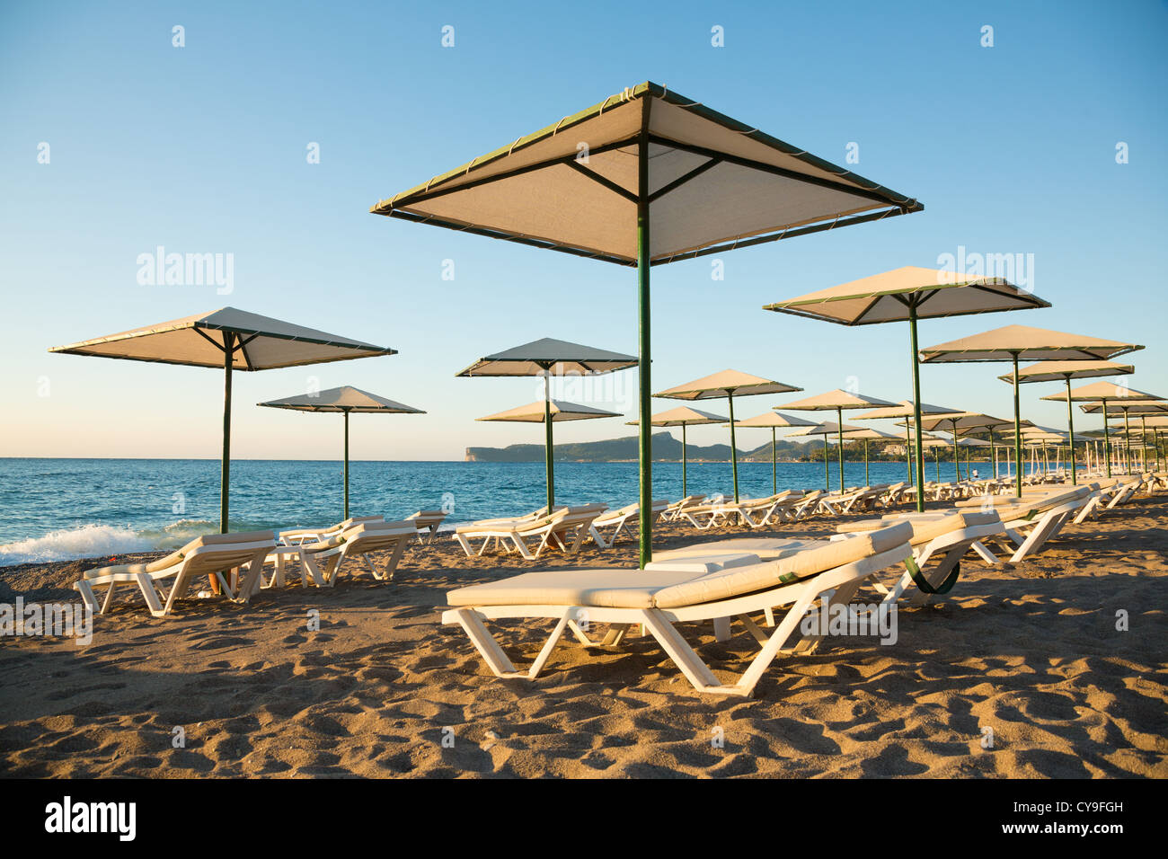 Leere schönen sonnigen Strand am Morgen mit Sonnenschirmen und Strandliegen Stockfoto