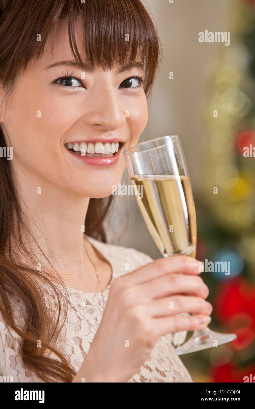 Young Woman Holding Champagnerglas vor Weihnachtsbaum Stockfoto