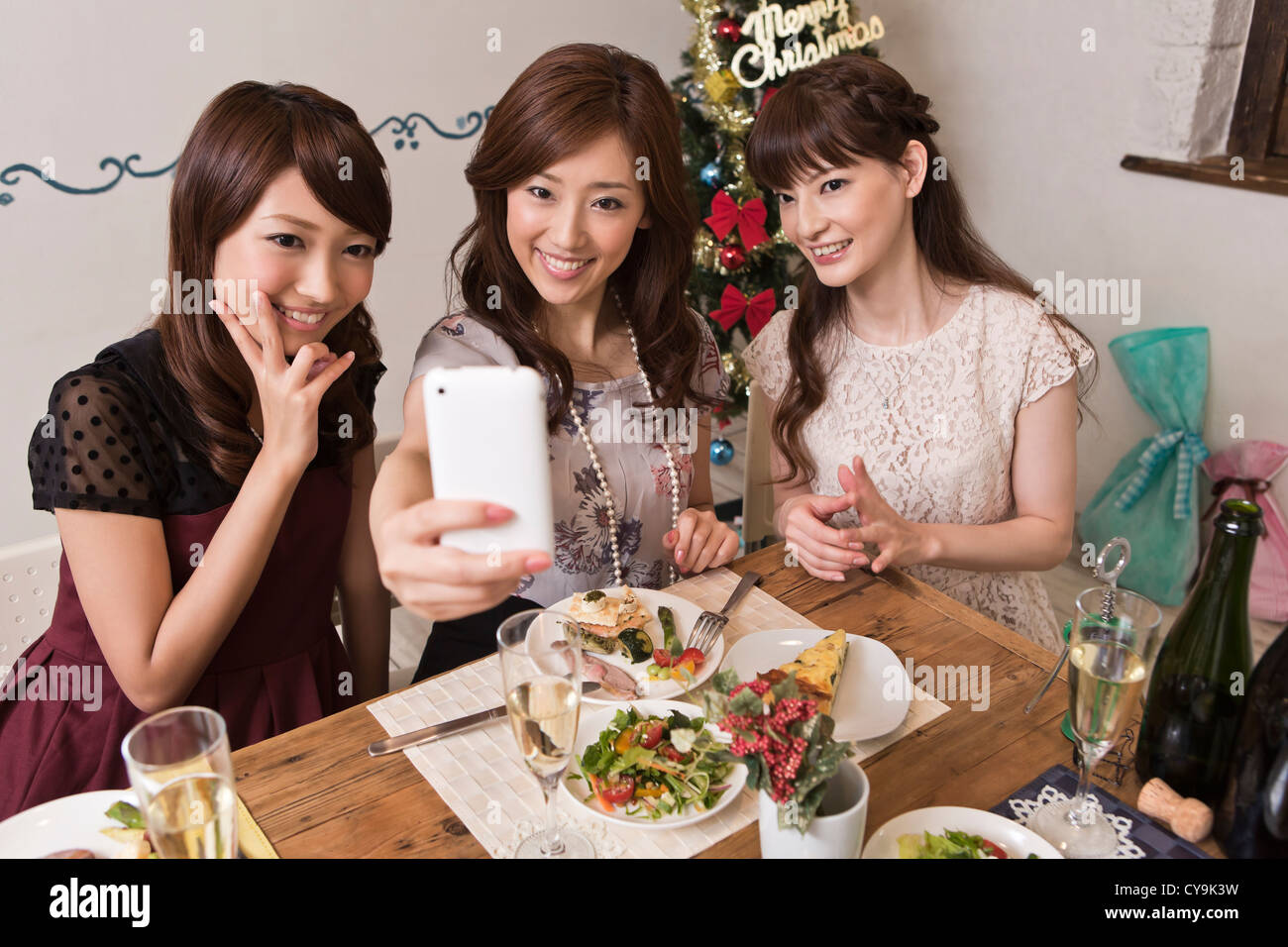 Drei junge Frauen fotografieren mit Smartphone Christmas Party Stockfoto
