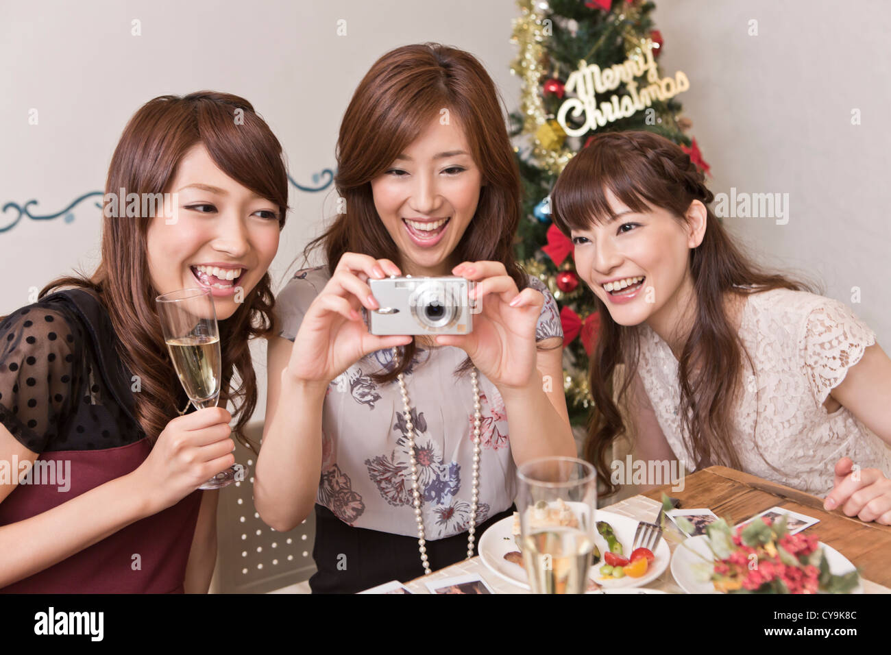 Drei junge Frauen fotografieren mit Digitalkamera bei Weihnachtsfeier Stockfoto