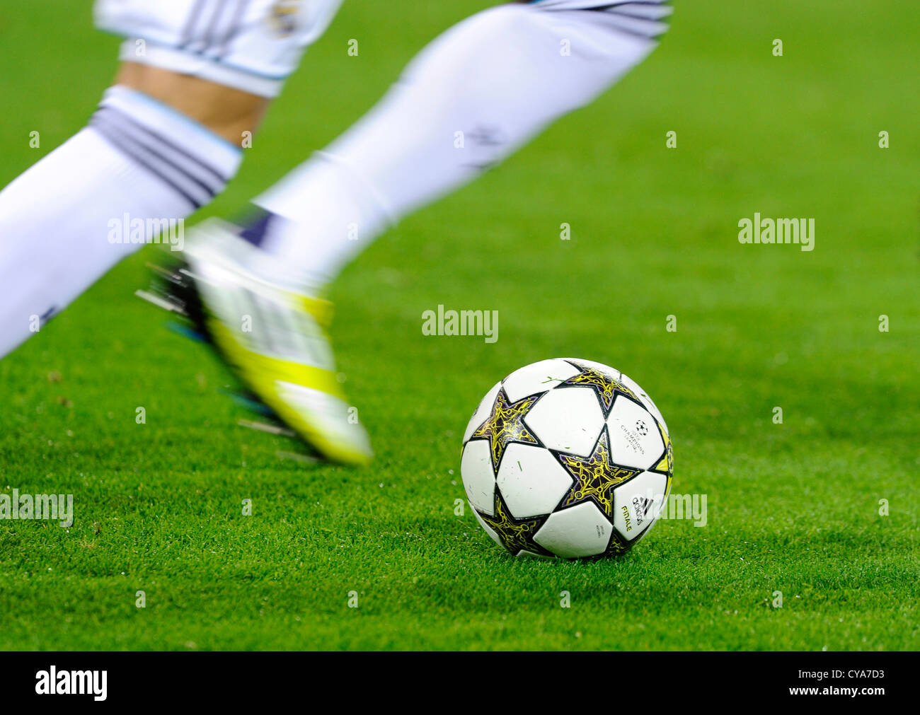 Beine eines Real Madrid Football-Spielers spielt mit UEFA Champions League Ball Adidas Finale 12 OMB auf Stellplatz Stockfoto