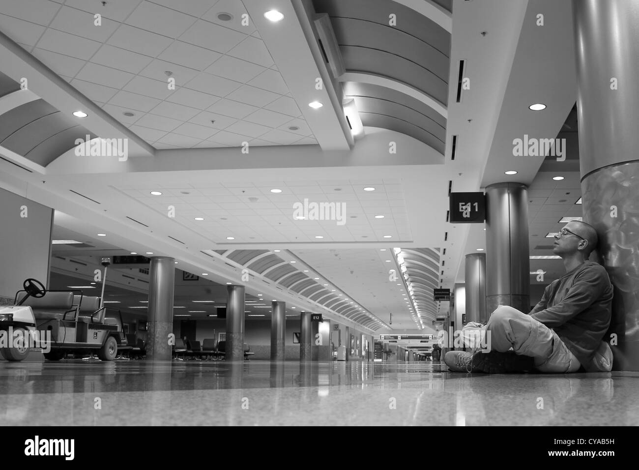 Ein Mann sitzt allein in einem leeren Flughafen terminal Flughafen Hartsfield-Jackson Atlanta, die am stärksten frequentierte Flughafen der Welt. Stockfoto