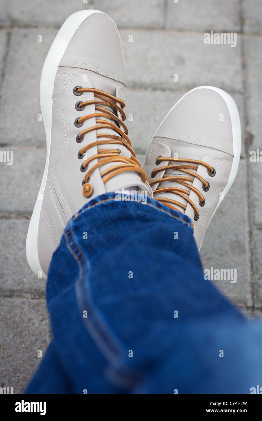 Halben Körper der männlichen Teenager posiert er Jeans und Sneakers, sitzen Kreuz Fuß Stockfoto