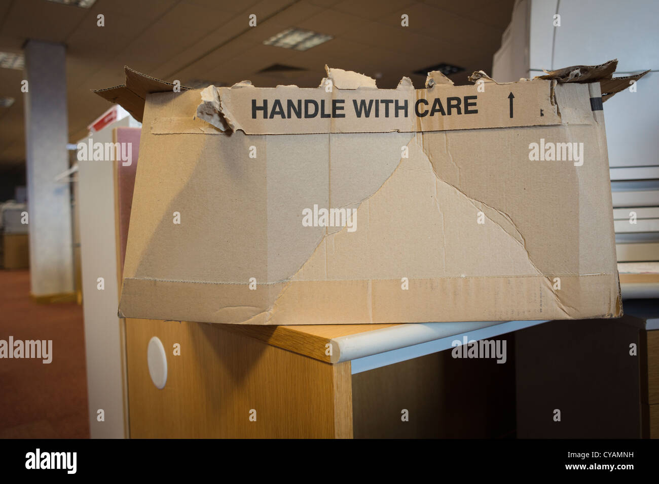 Eine offene Karton-Box auf dem Schreibtisch im Büro mit der Warnung, "Handle With Care" Stockfoto