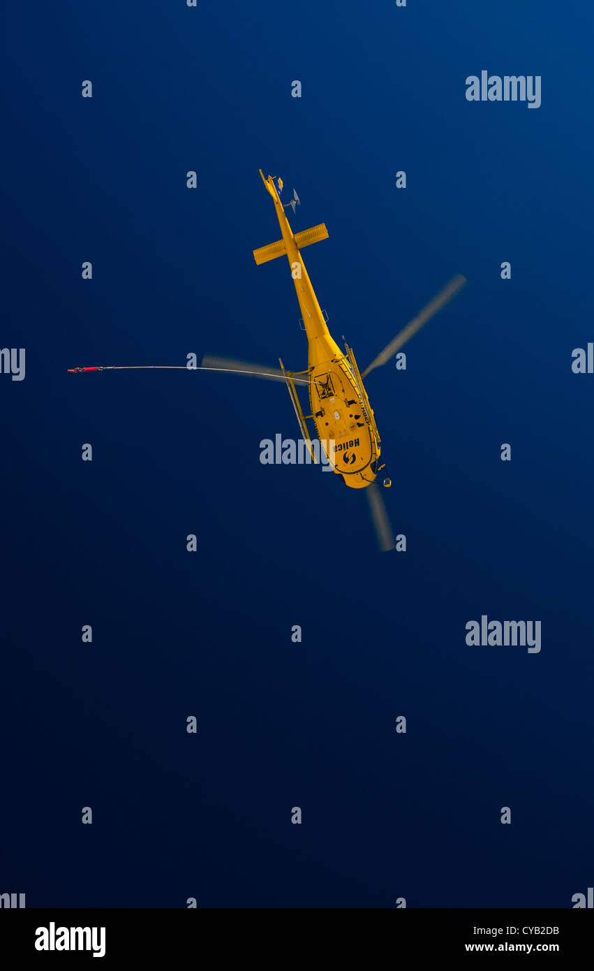 Ein helle gelbe Hubschrauber fliegt in bereit, seine kostbare Fracht hoch oben in den Bergen holen. Stockfoto