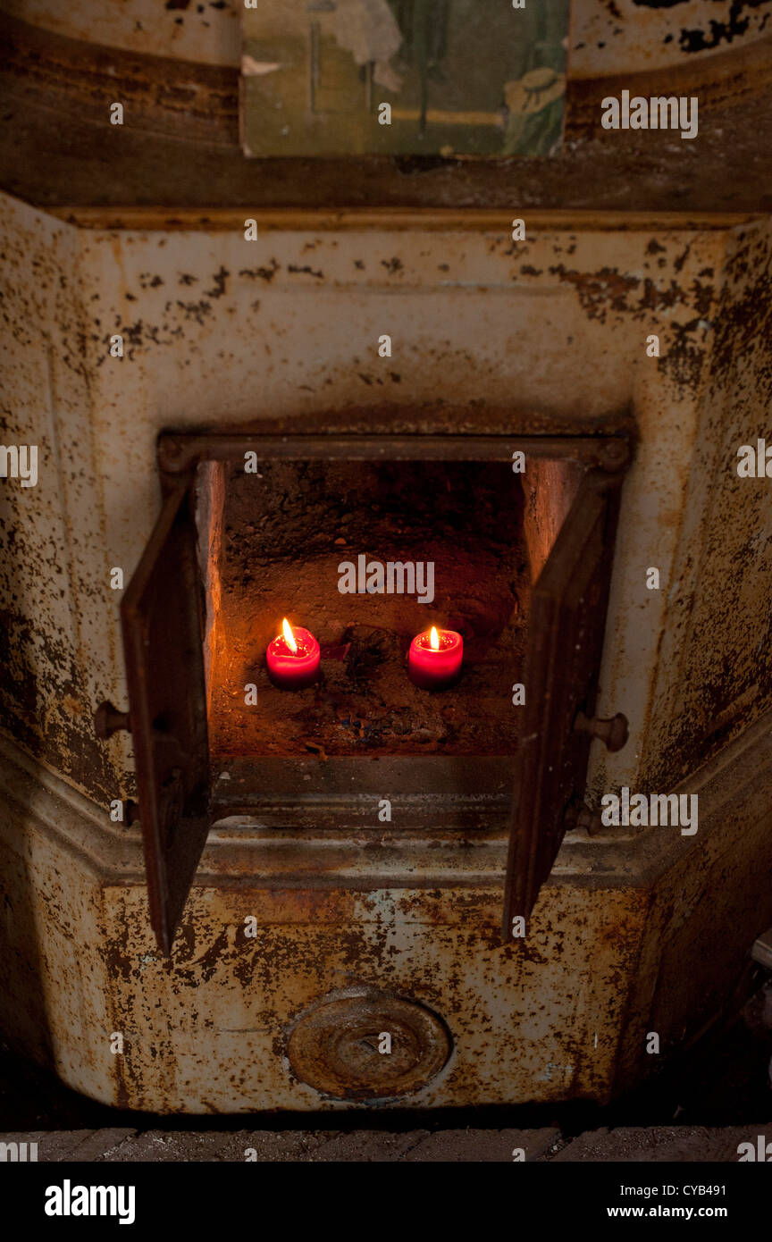 Alte Eisen-Kamin mit Kerzen brennen im Inneren Stockfoto