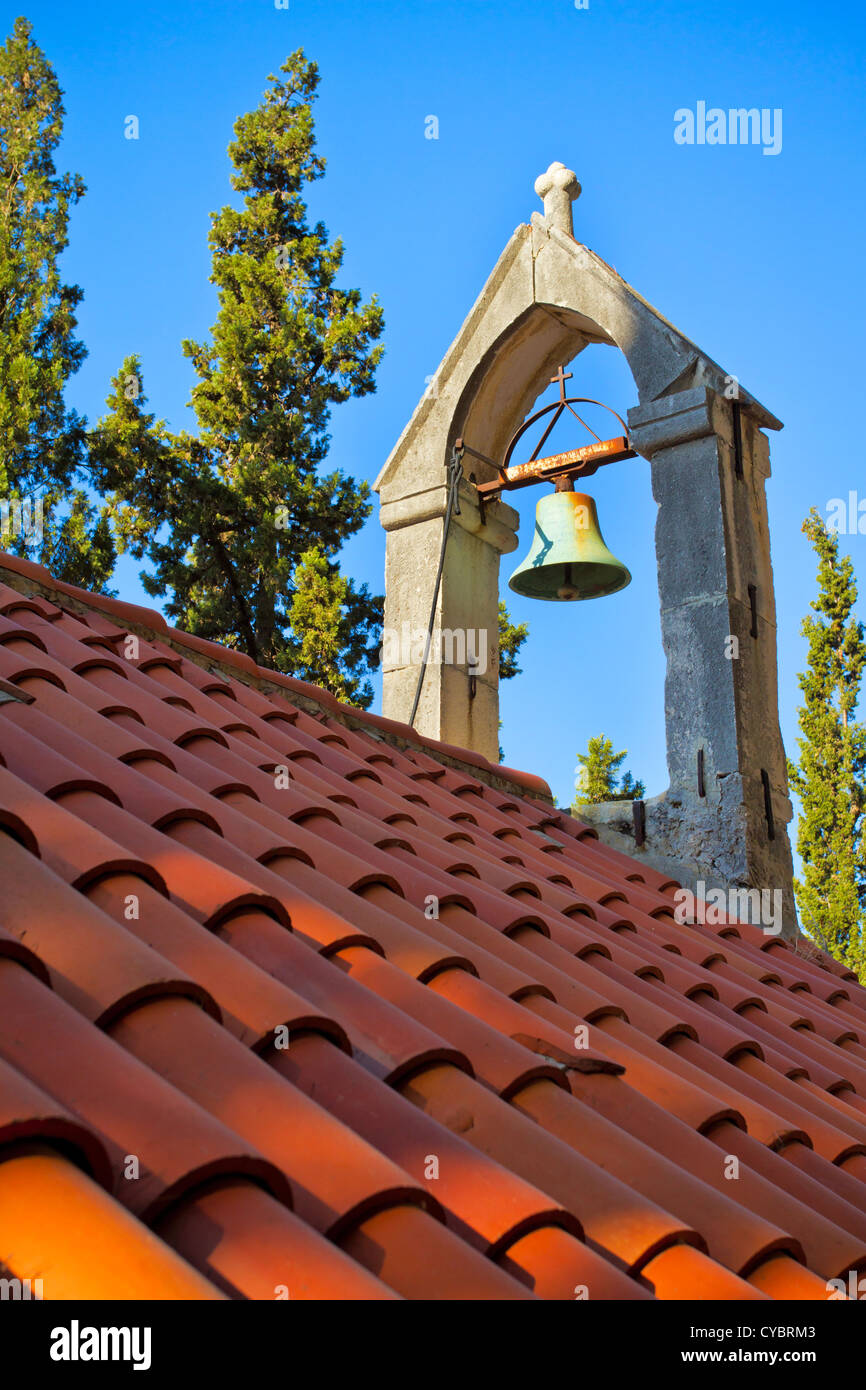 Glocke auf dem Dach der Kirche mit orange Fliesen bedeckt Stockfoto