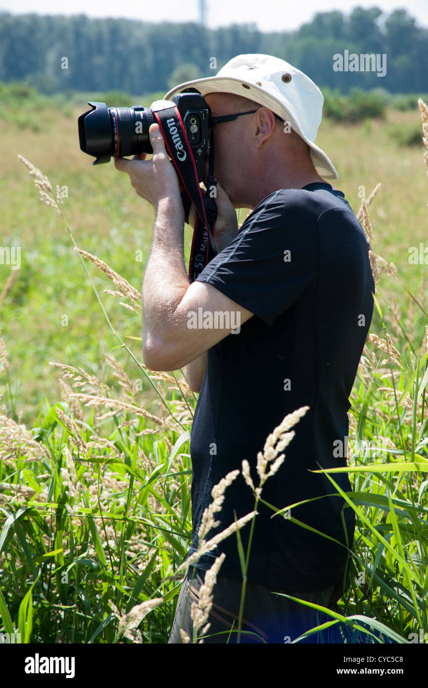 Männlichen Fotografen im Freien mit einer Canon 5D Mark II Kamera im Feld Stockfoto