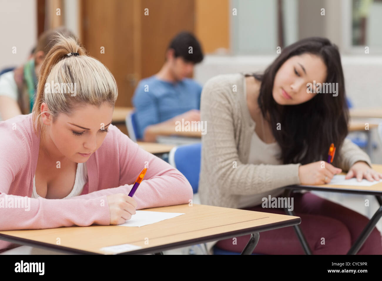 Brünette versucht, blonde Studentin in Prüfung zu kopieren Stockfoto