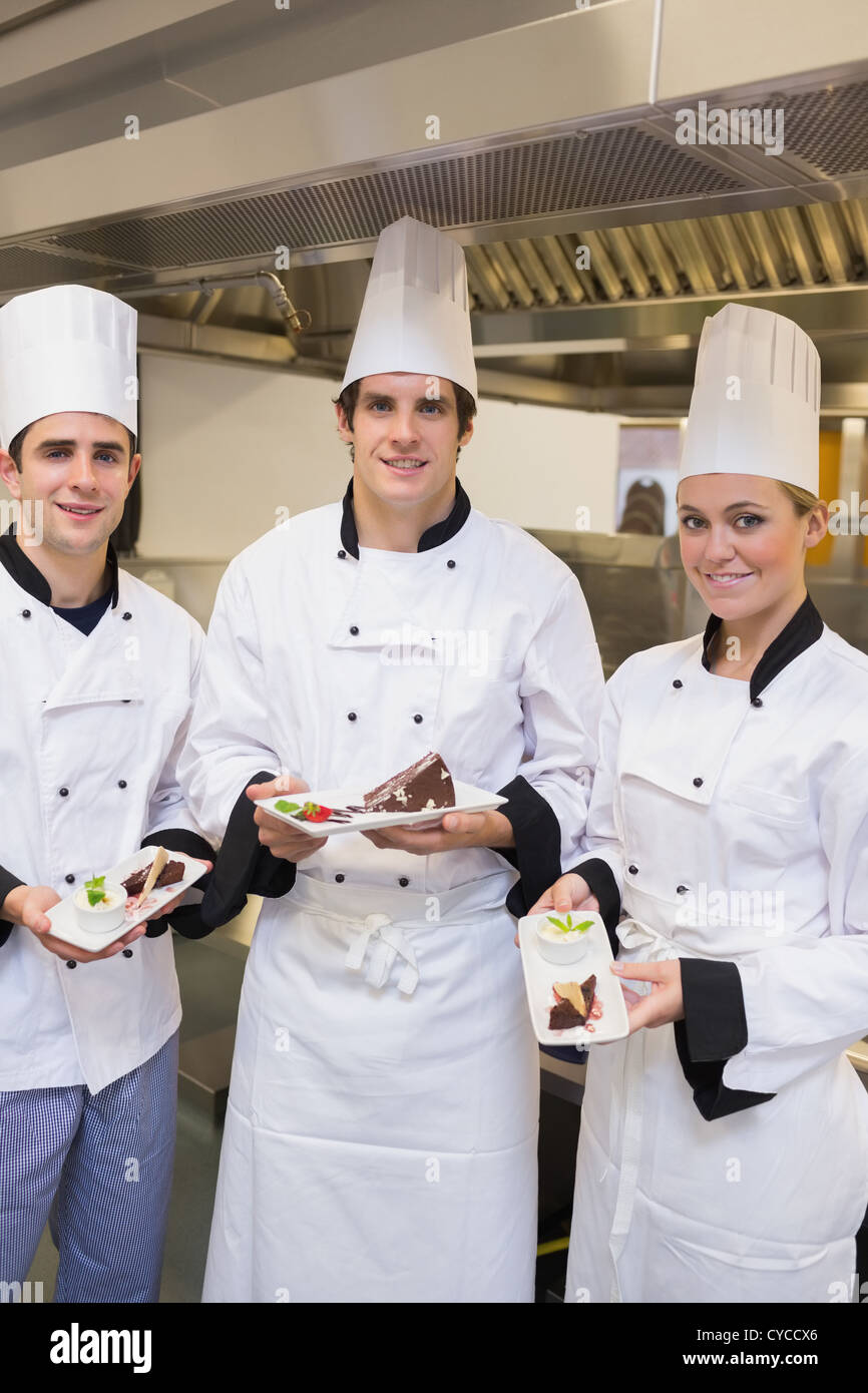 Drei glückliche Koch präsentiert Kuchen Stockfoto