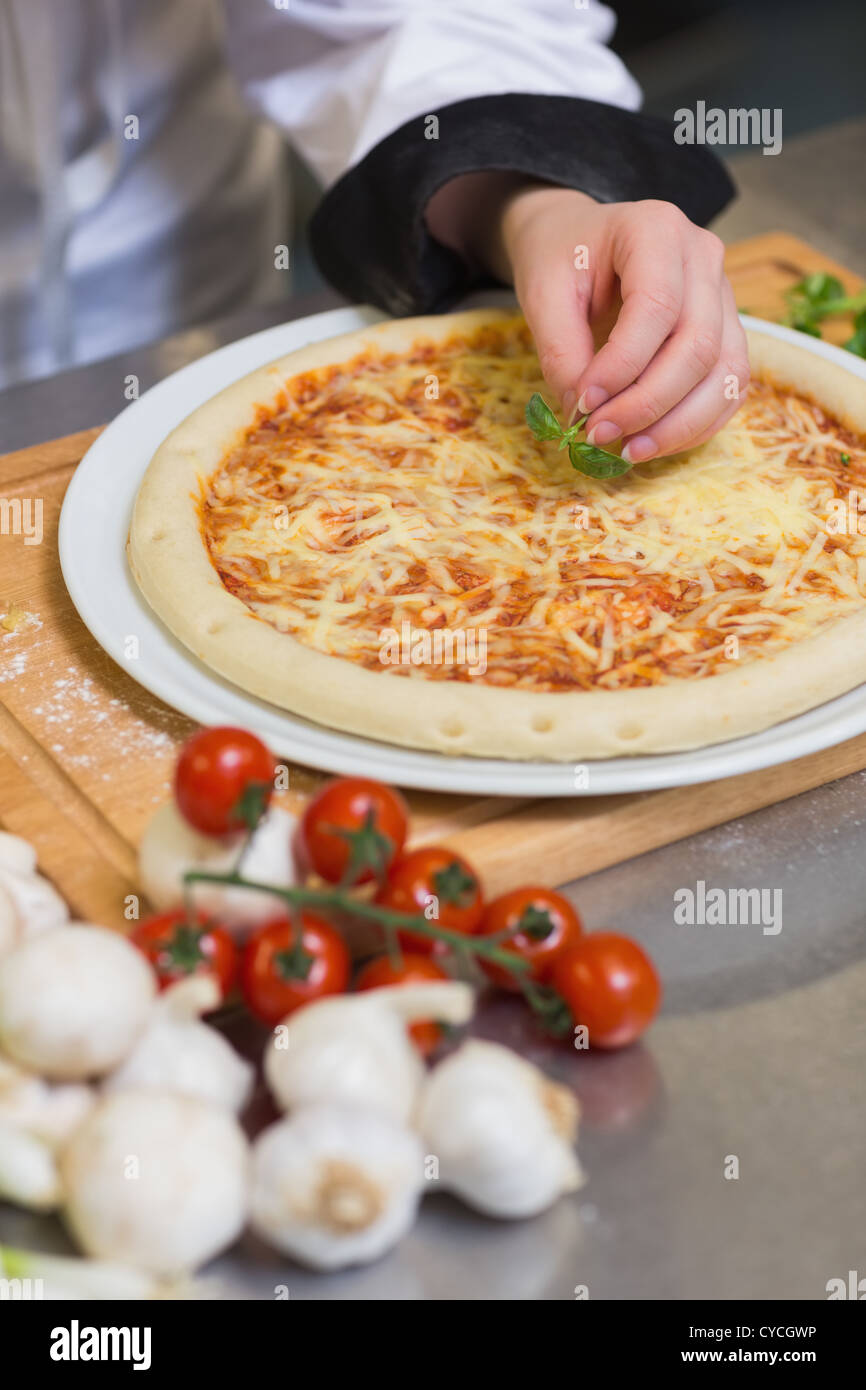 Pizza wird garniert mit Basilikum Stockfoto
