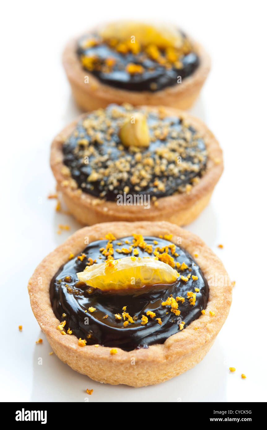Mini Schokolade Törtchen mit Stück Mandarine und Pistazien an der Spitze Stockfoto