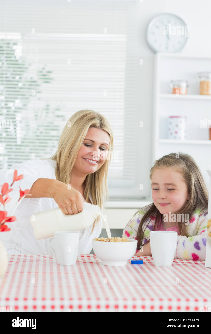 Mutter gießt Milch in Müslischale für Tochter Stockfoto