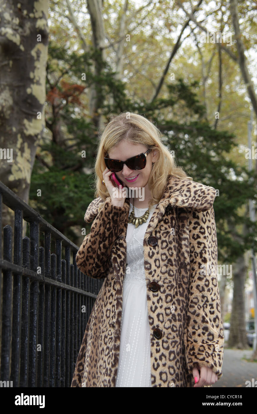 Frau in Leopard print Mantel mit Smartphone in Astoria, Queens, New York City, 26. Oktober 2012 © Katharine Andriotis Stockfoto